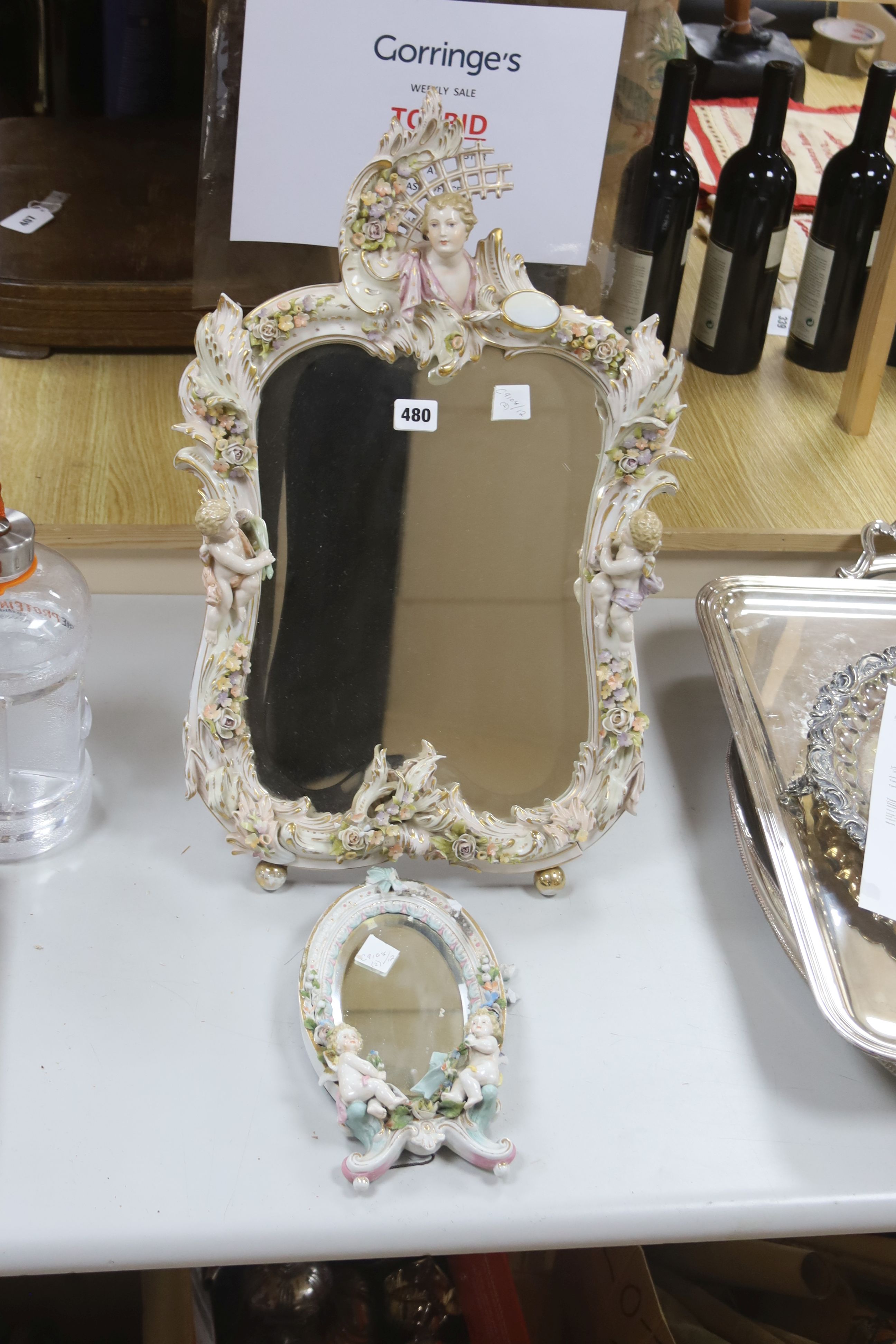 A large 19th century German porcelain easel mirror, height 60cm, and a smaller oval porcelain mirror